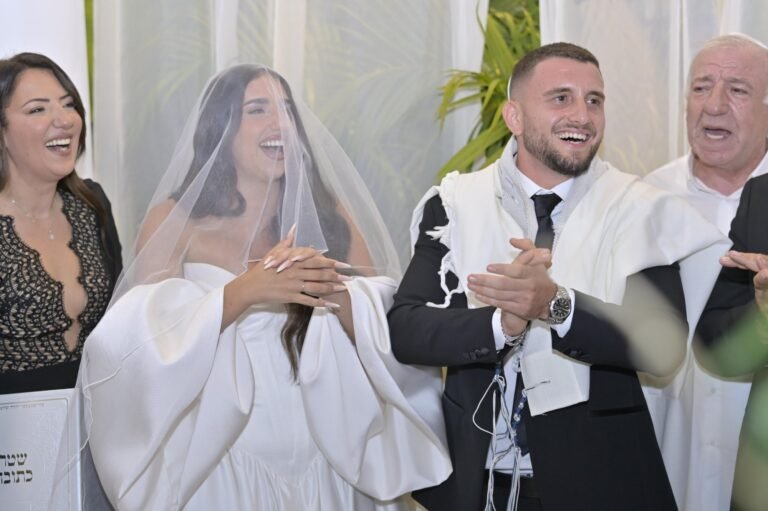 הזוג צוחק תחת הטלית בחופה